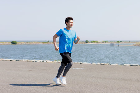 Young Asian man jogging at the seaside