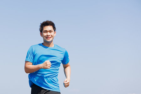 Young Asian man jogging outdoorsの写真素材