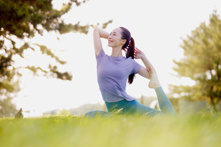 Young Asian woman practicing yoga in the parkの写真素材