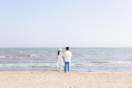 Young Asian couple standing at the beachの写真素材