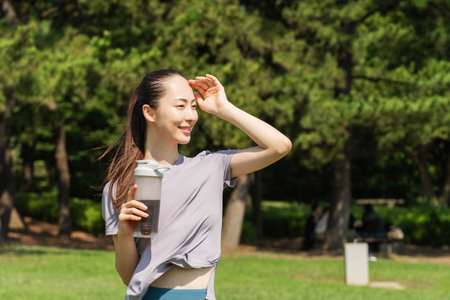 Young Asian woman with water bottle standing outdoors