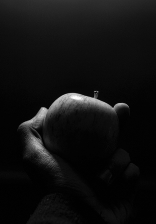 Man's hand holding an apple in black and white color.の写真素材