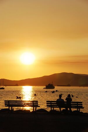 Silhouette of a couple enjoy beautiful sunset view in English Bayの写真素材