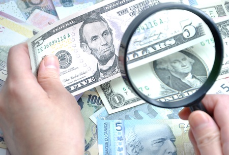 Woman checks her US five dollar bill with Magnifying glass