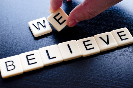 Hand putting we believe on dark wood backgroundの写真素材