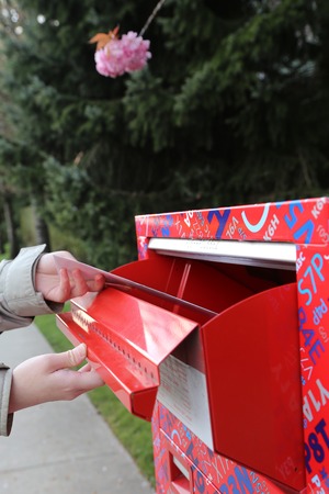Hand sending a tax report letter in a red mail boxの写真素材