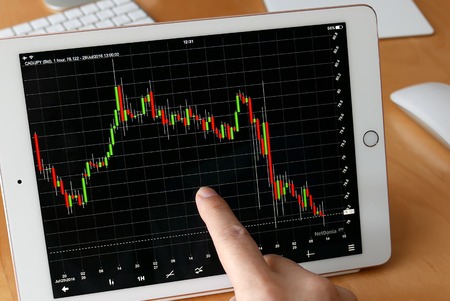 Coquitlam, BC, Canada - July 30, 2016 : Man using ipad to check exchange rate at homeのeditorial素材