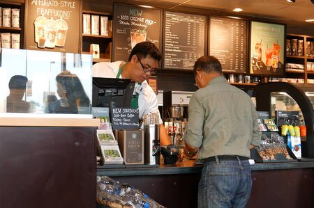 Coquitlam, BC, Canada - July 29, 2016 : Close up man buying coffee and paying by credit card inside Starbucks storeのeditorial素材