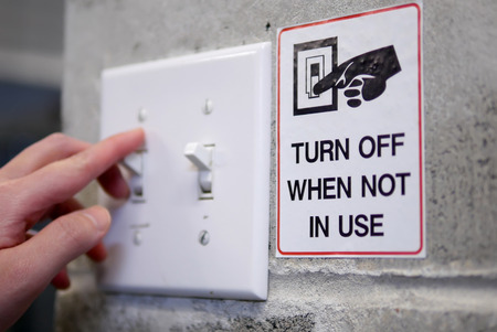 Woman preparing to turn off light switch by saving power concept