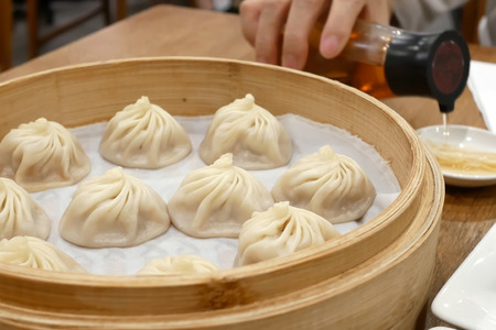 People pouring vinegar before eating soup dumpling buns in restaurantの写真素材