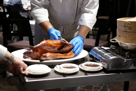Motion of chef cutting roasted duck into a plate for customer inside Chinese restaurantの写真素材