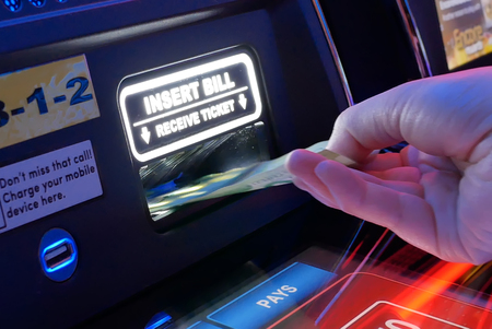 Coquitlam, BC, Canada - June 12, 2018 : Motion of woman inserts money on slot machine inside Casino