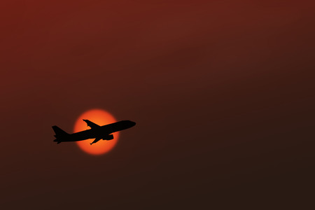 Silhouette of an airplane taking off on sunset background