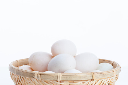 Raw dirty duck eggs in the bamboo bowl basket on white backgroundの写真素材