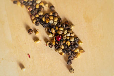 Close up shot of a mixed peppercorns on the round wooden board.