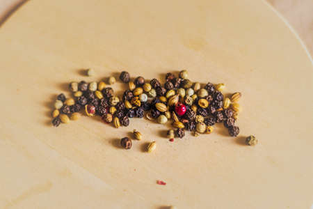 Close up shot of a mixed peppercorns on the round wooden board.