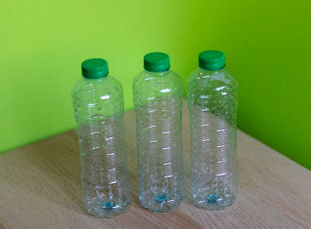 Shot of a plastic bottles on wooden table with bright green background.