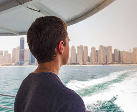 Teenage boy observing the city from the boat