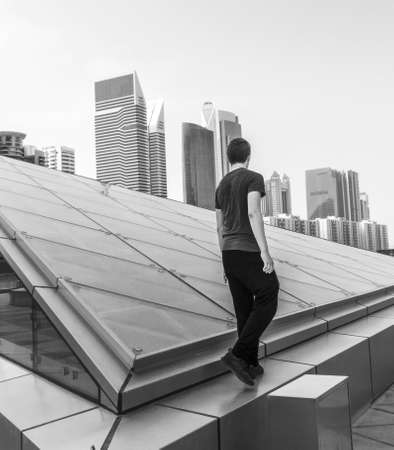 Black and white shot of a young boy with modern city on the backgroundの写真素材