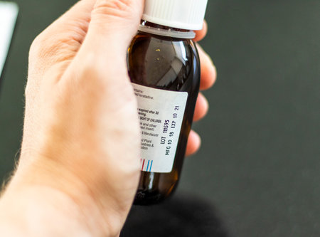 Close up shot of a hand holding a bottle with medicine with expired dateの写真素材