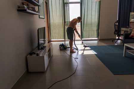 Shot of man vacuuming the carpet i the roomの写真素材