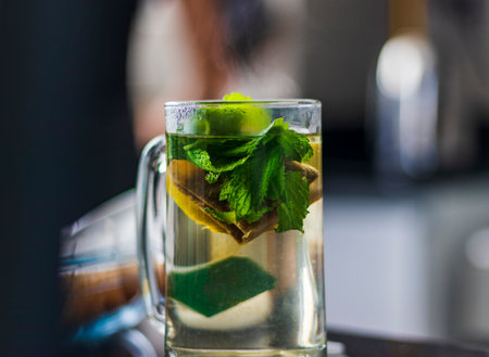 Close up shot of a transparent cup with brewing tea bag in it, lemon and mintの写真素材