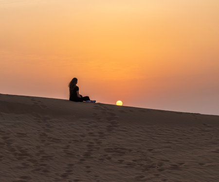 Silhouette of a woman in the desert during sunsetの写真素材
