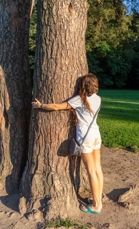 Shot of the young woman hugging the branch of the treeの写真素材