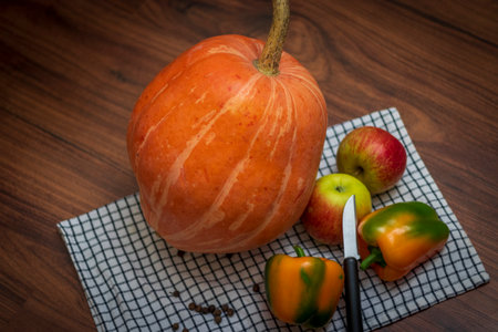 Close up shot of the pumpkin, capsicums and apples on the wooden tableの写真素材