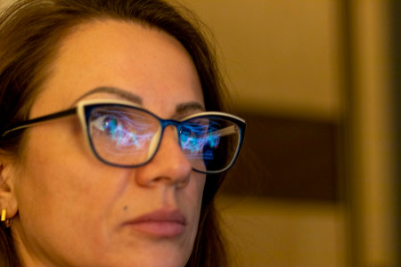Close up shot of the woman in front of the computer screen with trading bar charts reflected in her...