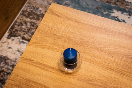 Close up shot of the blue, scented candle on the wooden tableの写真素材
