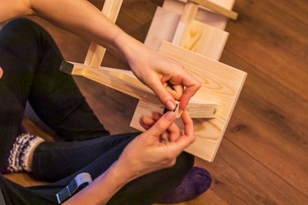 Woman is assembling wooden shelfの写真素材