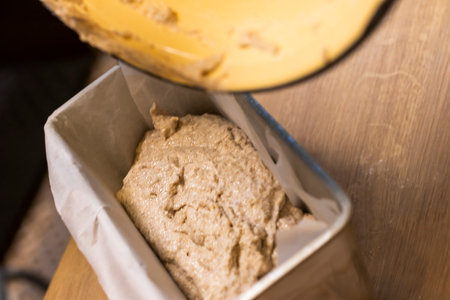 Placing the dough into the bread loaf pan on the kitchen counter top