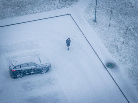 Woman walks and talks on the phone during heavy snowfallの写真素材