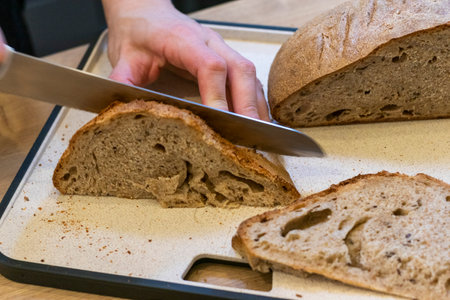 Woman cuts freshly baked loaf of home made rye bread