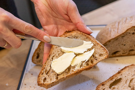 Woman spreads home made butter on to cuts of freshly baked home made rye bread