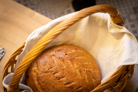 Shot of the freshly baked loaf of home made rye bread on the linen cloth in the wicker basketの写真素材