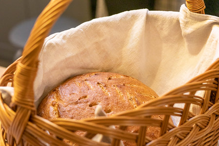Shot of the freshly baked loaf of home made rye bread on the linen cloth in the wicker basketの写真素材