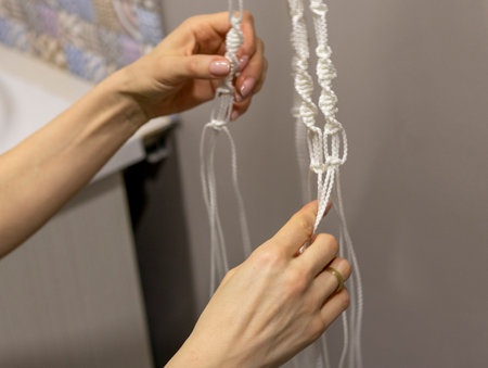 Woman weaving macrame flowerpot.