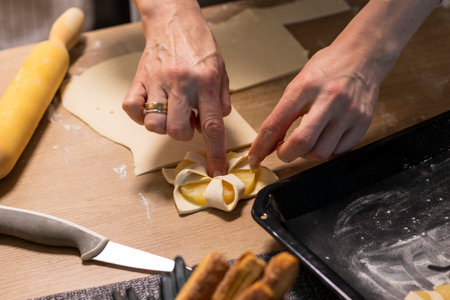A woman wraps a pineapple wedge in puff pastryの写真素材