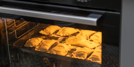 Puff pastries with cottage cheese filling baking in the ovenの写真素材