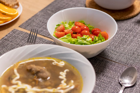 Bowl with cherry tomatoes and lettuce leaves, bowl with soup next to itの写真素材
