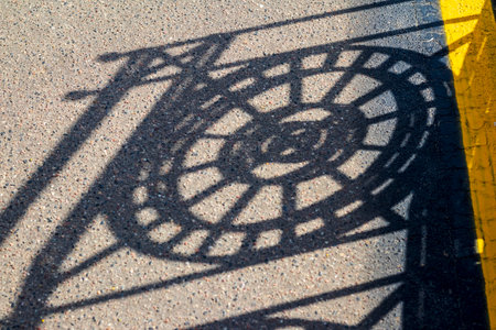 Shadow casting from the metal decorative fence to the asphaltの写真素材