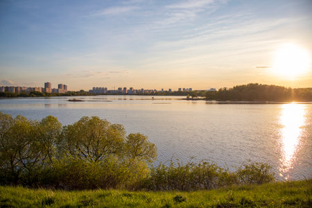 Sun is setting by the lake with city buildings on the backgroundの写真素材