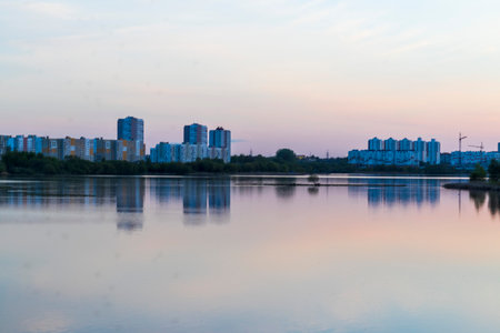 Sun is setting by the lake with city buildings on the backgroundの写真素材
