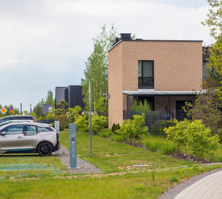 Facade of the stylish, urban, modern house, ergonomically designed and made of ecological materials. Electrical vehicle charging station next to it.の写真素材