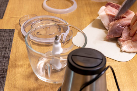 Woman cuts the meat, prepares it to grind it in electrical chopperの写真素材