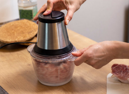 Woman mince the meat in the electrical chopper on the kitchen counter topの写真素材
