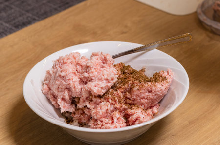 Just ground meat mince in the glass bawl of the electrical chopper on the kitchen counter top being seasoned and mixedの写真素材