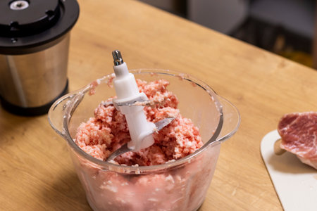 Just ground meat mince in the glass ball of the electrical chopper on the kitchen counter topの写真素材